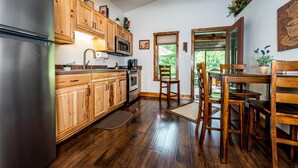 Eine Küche mit Holzausbau, einem Edelstahl-Kühlschrank, einer Mikrowelle und einem Essbereich mit Holztischen und einem Tisch.