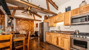 Eine Küche mit Holzausstattung, Edelstahlgeräten und einem Essbereich mit Holztisch und Stühlen.