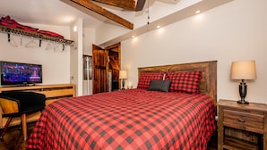 Ein Schlafzimmer mit einem großen Bett, einem Holzkopfende, einem Schreibtisch mit Stuhl, einem Fernseher und einem Deckenventilator.