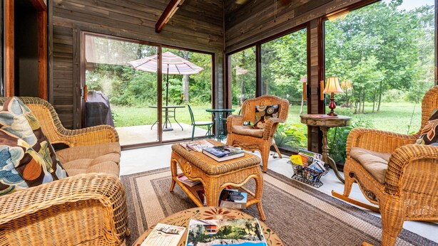 Ein gemütliches Zimmer mit Korbmöbeln, großen Fenstern und einem Deckenventilator.