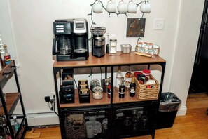 A kitchen counter with coffee makers, jars, and a basket of bread.