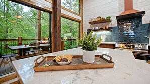 A kitchen with a marble countertop, a potted plant, and a tray with bread and jam. - Cozy Nights Cabin Luxury and Location (Broken Bow)