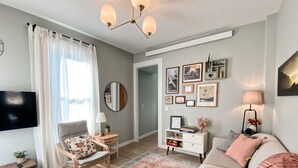 A modern living room with a sofa, armchair, TV, and a coffee table. - Charming River View Apt | Walk to Shops & Cafes (The Dalles)
