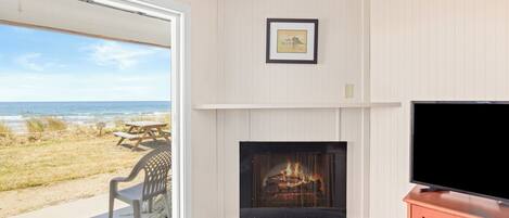 Una habitación con chimenea, televisión y vista a la playa.