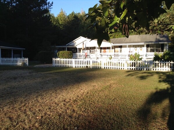 A two-story house with a white picket fence, a covered porch, and a well-maintained lawn.
