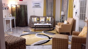 Uma sala de estar com sofá, poltronas, mesa de centro e tapete estampado.