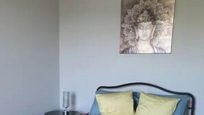 A bedroom with a bed, pillows, a bedside table, and a wall decoration.