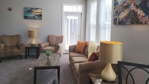 A living room with striped armchairs, a sofa, a coffee table, and a painting on the wall.