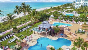 Un complexe hôtelier doté de plusieurs piscines, d’une plage et de palmiers.