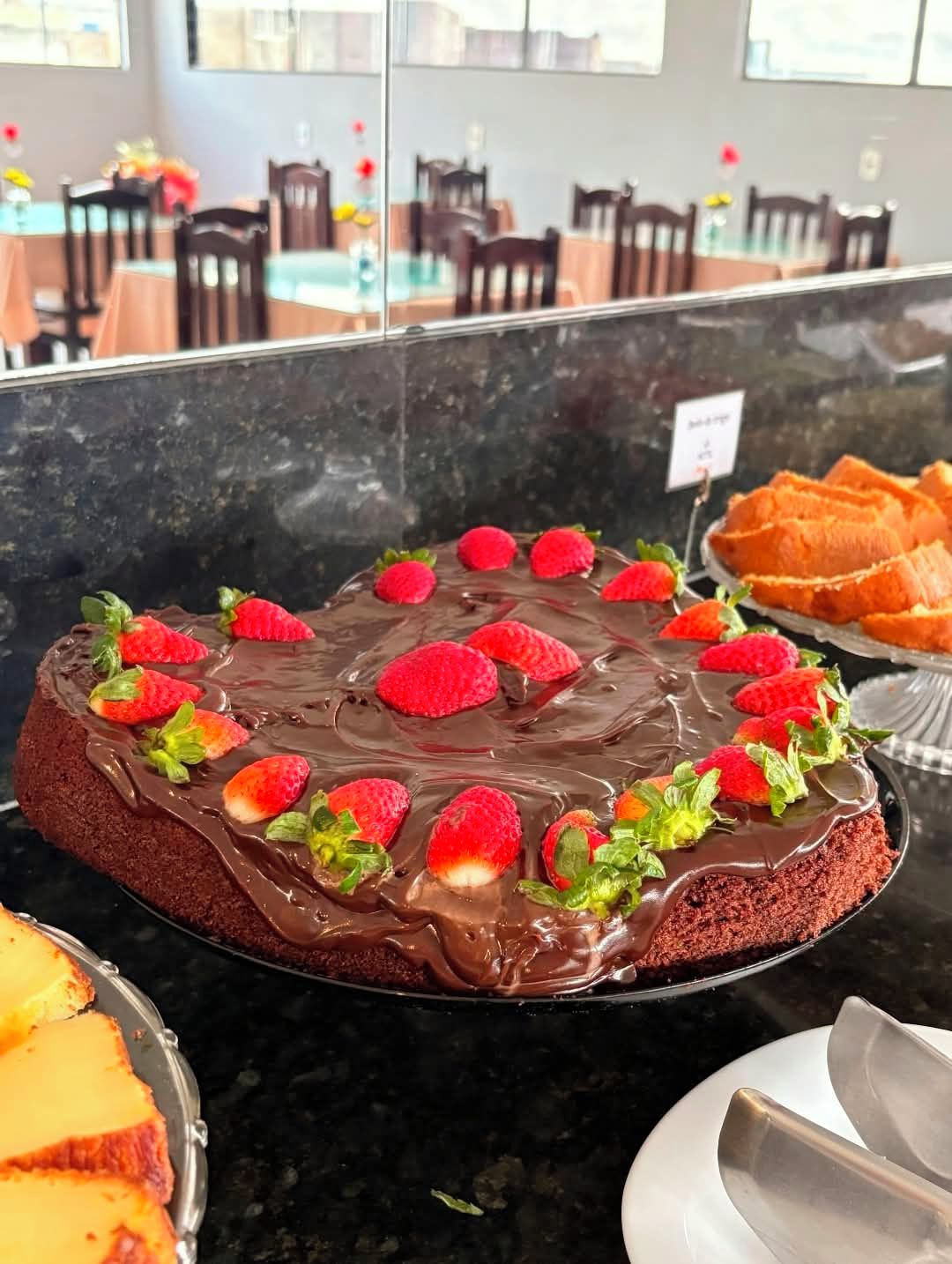 Een chocoladecake met aardbeien op een marmeren aanrecht in een eetruimte.