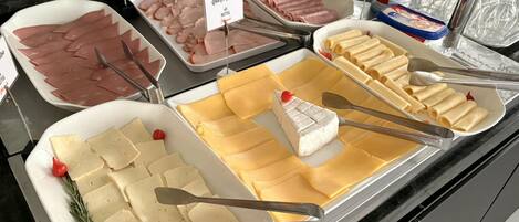 A buffet with various food options including meats, cheeses, and pasta.