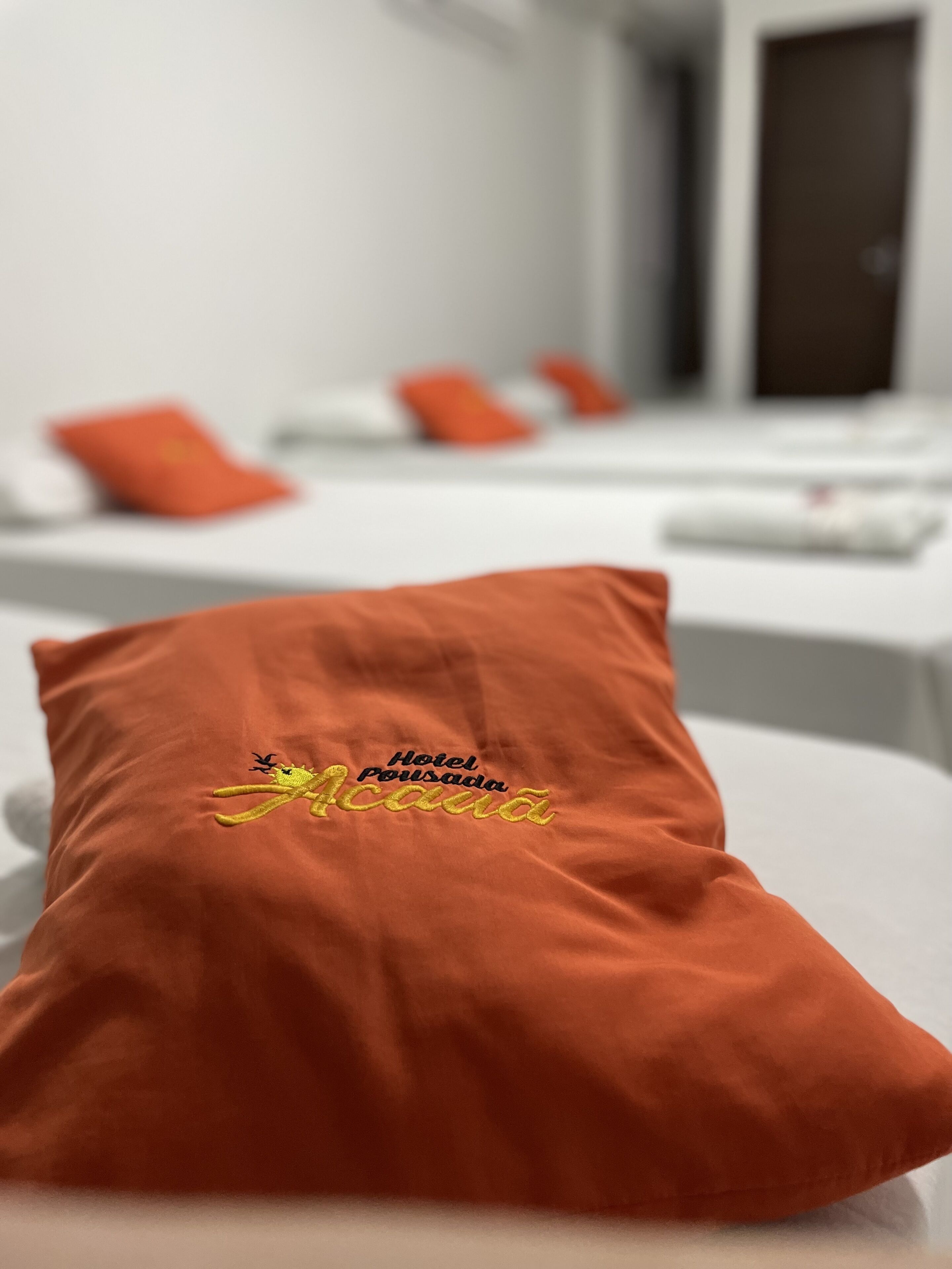 Ein Hotelzimmer mit einem Bett, einem gestickten Kopfkissen und einer Tür im Hintergrund.