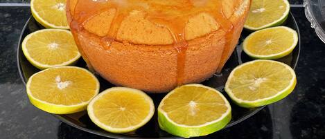A cake with a glaze and surrounded by lime slices on a black surface.