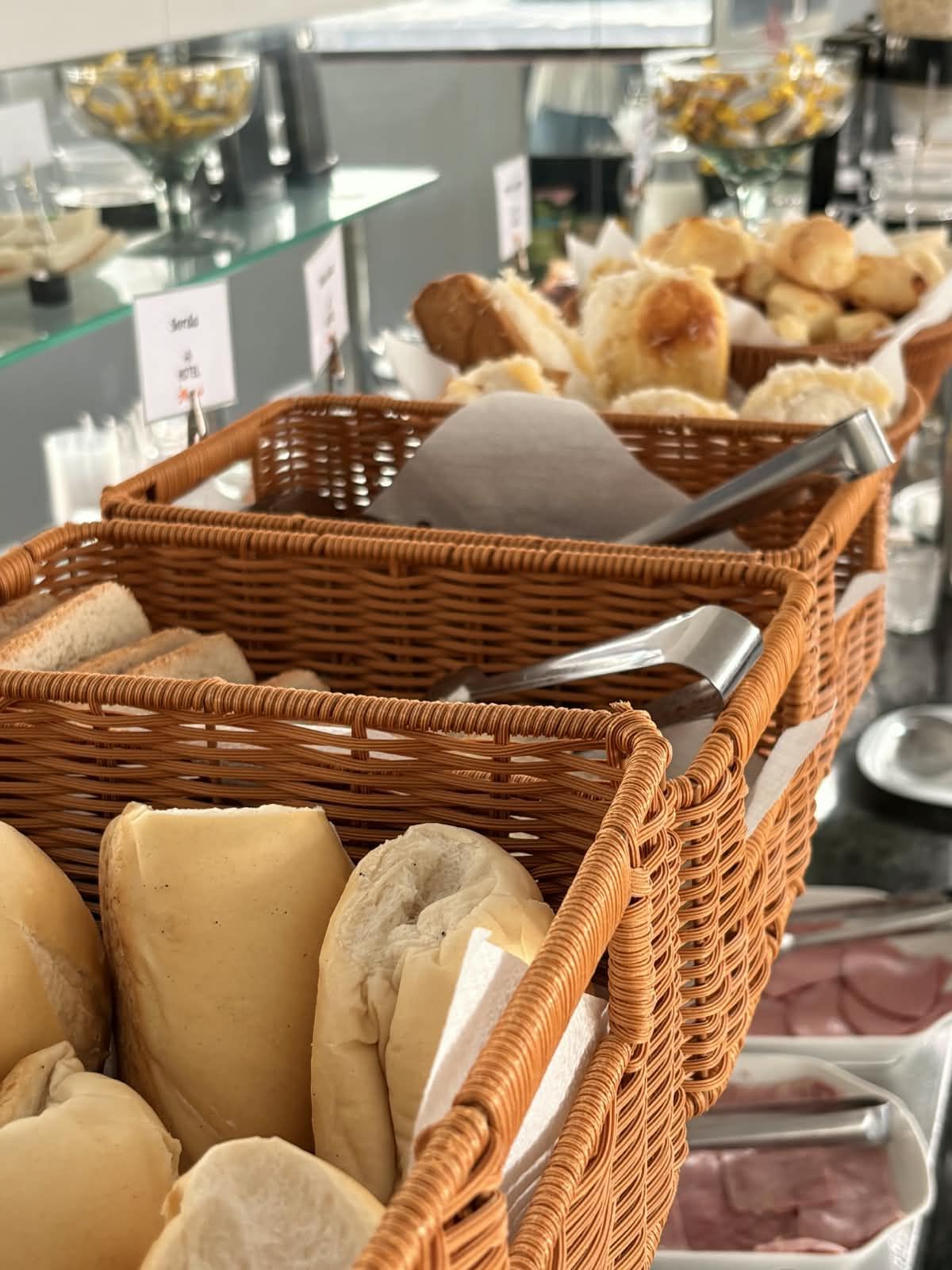 Un bufé con cestas de mimbre que contienen panes y pasteles varios.