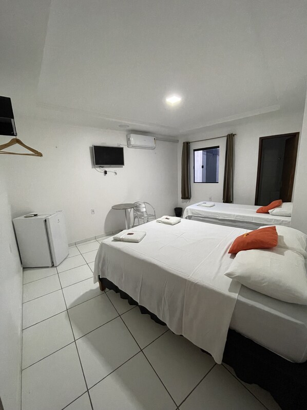 Una habitación de hotel con una cama, un escritorio, una silla, un televisor y aire acondicionado.