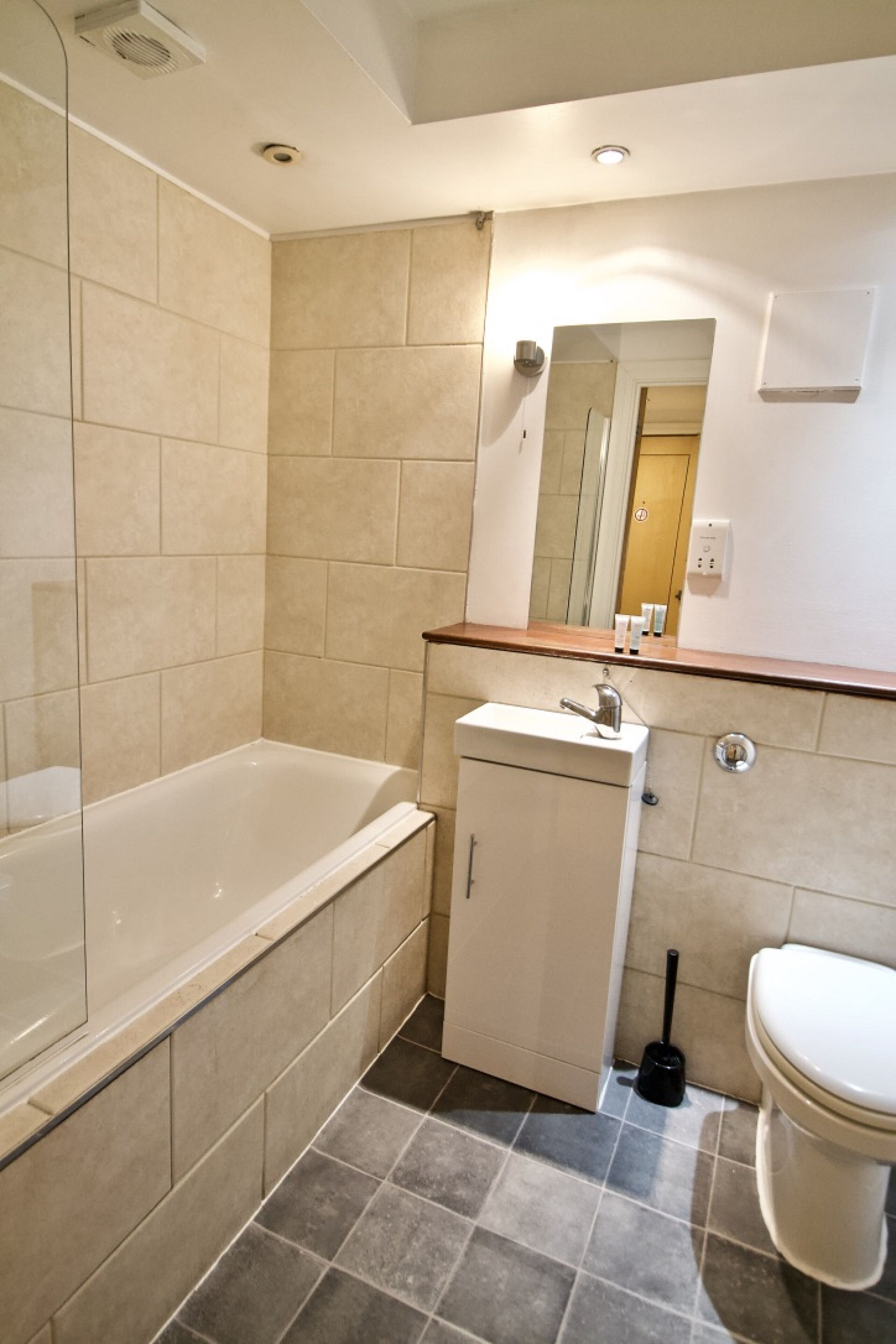A bathroom with a bathtub, a sink, a toilet, and a mirror.