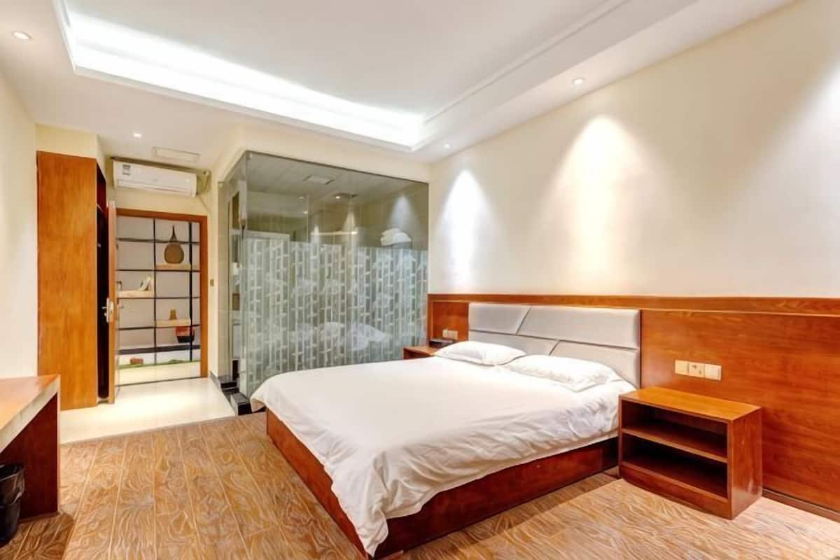 A bedroom with a large bed, a wooden headboard, a bedside table, and a built-in shelf.