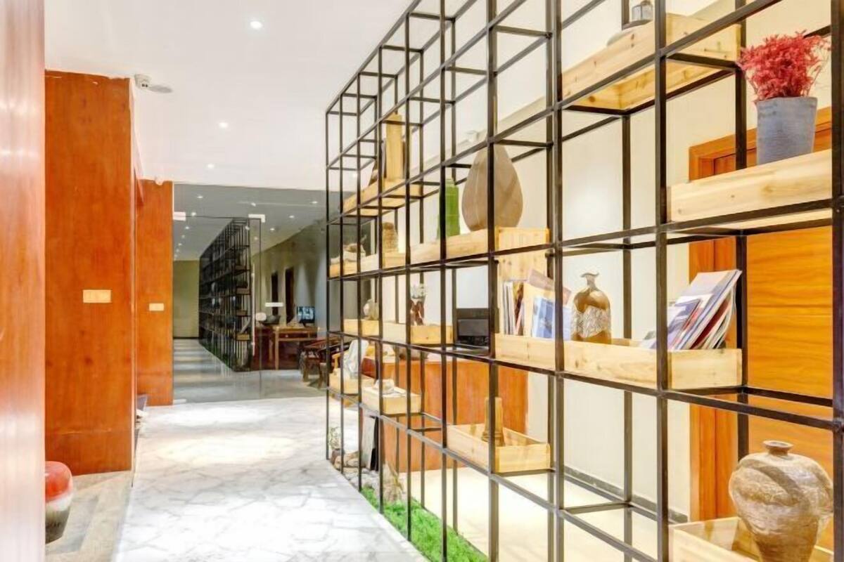 A hallway with a wooden floor, a metal grid structure, and shelves with various items.