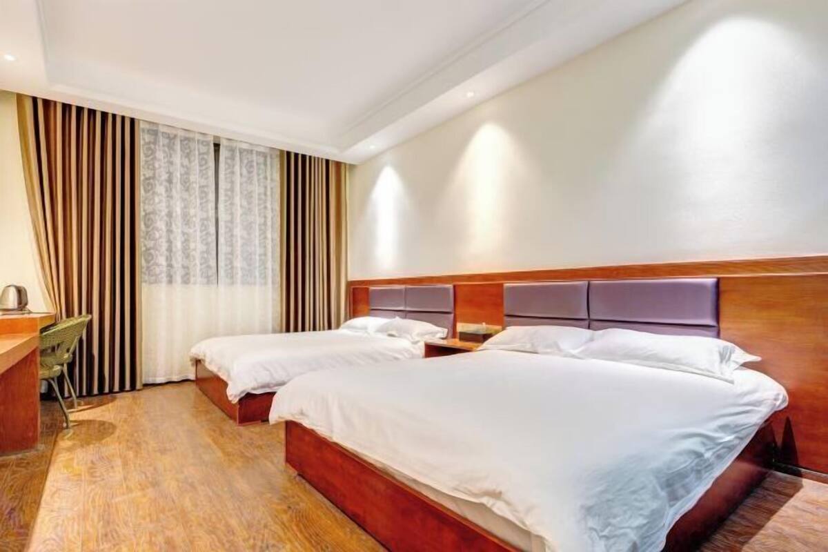 A hotel room with two beds, a desk, and a chair.
