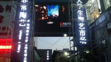 A street view with a large digital billboard displaying a cityscape.