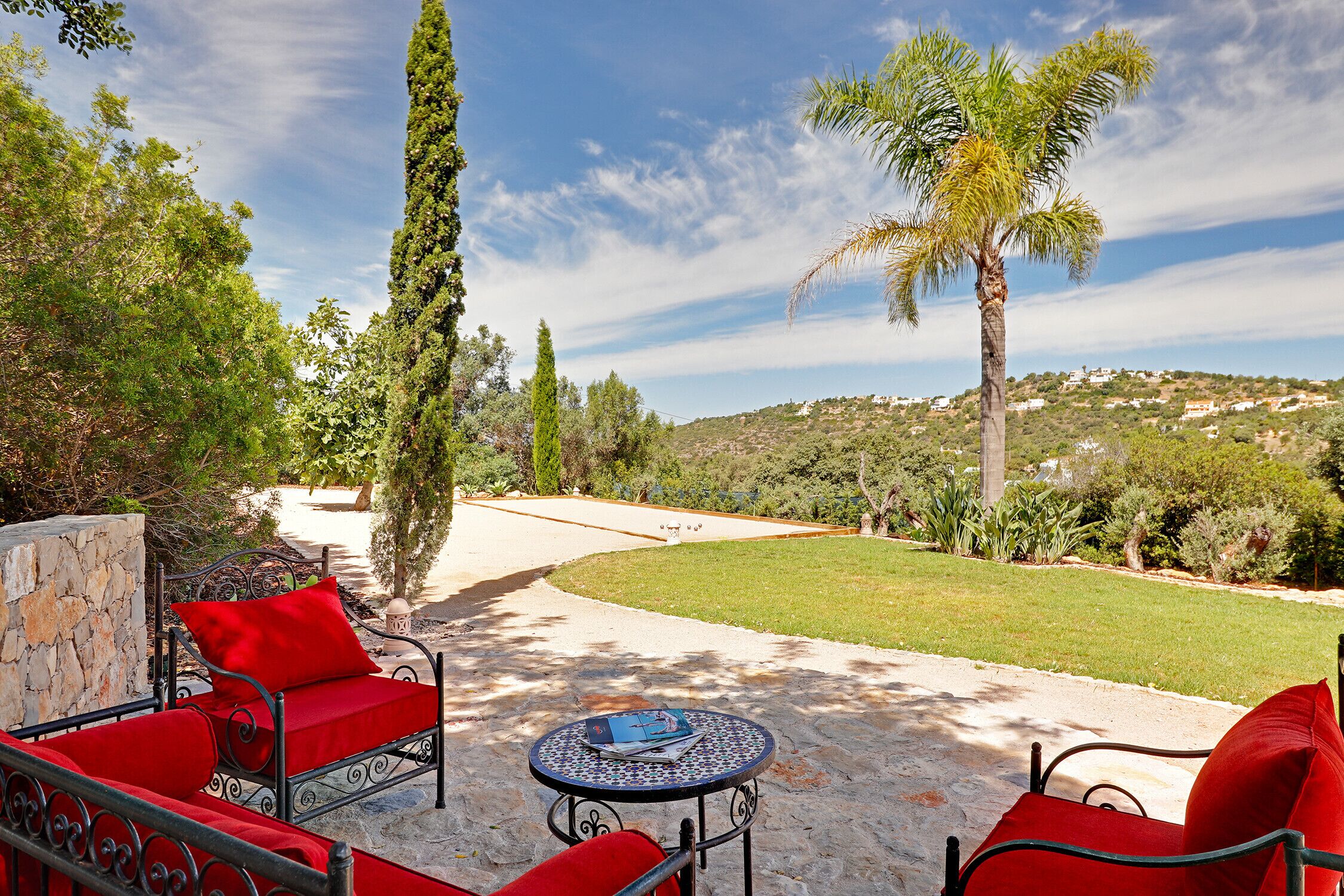 A patio with outdoor furniture, a palm tree, and a view of a hillside.