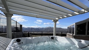 Un jacuzzi con vistas a montañas bajo una pérgola.