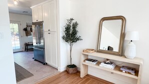 A kitchen with white cabinets, a refrigerator, and a wooden floor. - Chic wine country cottage and garden (Healdsburg)
