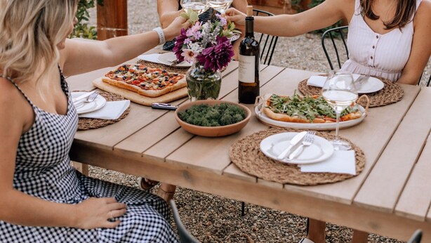 An outdoor dining area with a wooden table, chairs, and a pergola. - Chic wine country cottage and garden (Healdsburg)