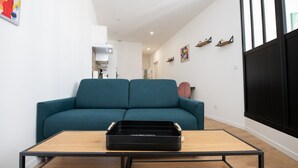 A living room with a teal sofa, a wooden coffee table, and a black suitcase on the table. - L'Arty-Beautiful well-furnished 31m² flat in Valmy (Lyon)