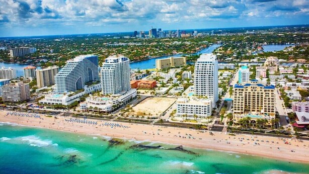 A coastal cityscape with high-rise hotels, a beach, and a river.