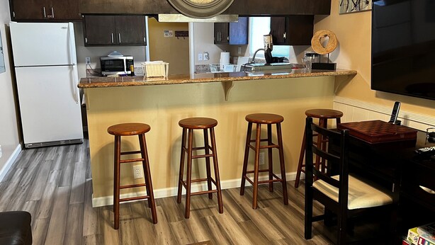 A kitchen with a central island, wooden stools, a dining table, and a TV. - Comfortable, convenient 2BR 2BA apt in Alameda (Alameda)