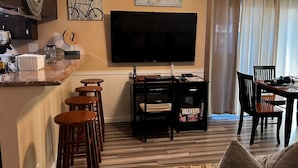 A living room with a TV, a dining table, and bar stools. - Comfortable, convenient 2BR 2BA apt in Alameda (Alameda)