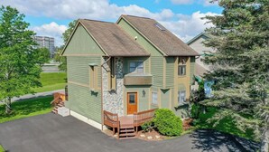 A two-story house with a green exterior, a stone accent wall, a wooden front porch, and a number '248' on the door.