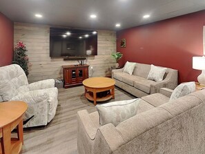 A living room with a sofa, armchair, coffee table, TV, and a cabinet.
