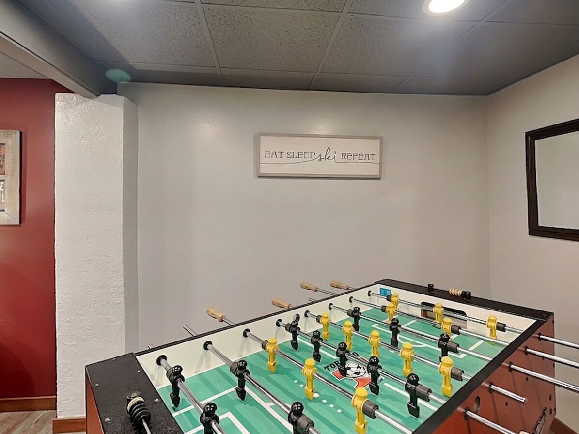 A foosball table in a room with a sign on the wall that reads 'EAT SLEEP SLEEP REPEAT'.