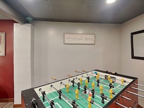 A foosball table in a room with a sign on the wall that reads 'EAT SLEEP SLEEP REPEAT'.