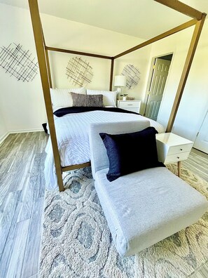 Um quarto moderno com uma cama de dossel, uma mesinha de cabeceira e um banquinho.