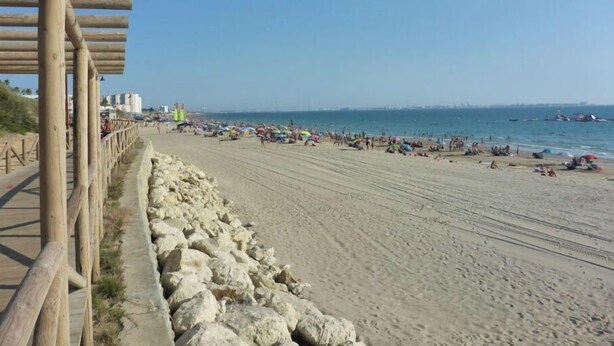A beach with a wooden walkway and a stone barrier. - HOLIDAY BEACH VACATIONS (El Puerto de Santa María)
