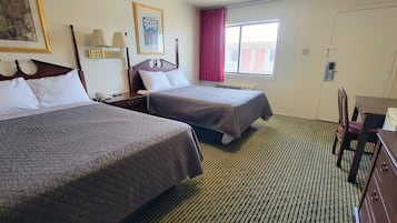Habitación de hotel con dos camas, un escritorio, una silla, un aparador y una ventana con cortinas.