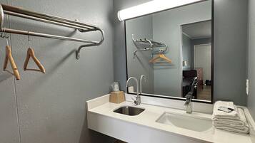 A modern bathroom with a white sink, a mirror, and a towel rack.