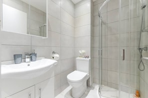 Bathroom features a sink, toilet, and glass-enclosed shower area.