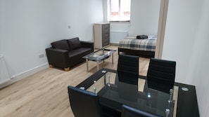 Cozy living space with a leather sofa, dining table, and comfortable bed.