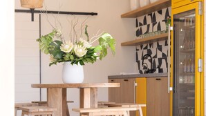 Een moderne keuken met houten tafels, hangende rieten lampen en potplanten.