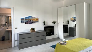 Ein modernes Schlafzimmer mit grauem Schminktisch, einer gelben Tagesdecke und einem Kamin.