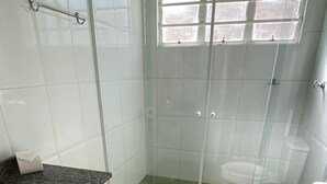 A bathroom with a glass-enclosed shower, a white toilet, and a granite countertop with a sink. - Villa 209 sua casa em Campos do Jordão (Campos do Jordão)