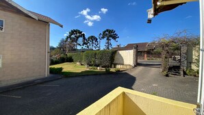 A residential driveway with a paved path leading to a gated entrance, surrounded by a well-maintained lawn and mature trees. - Villa 209 sua casa em Campos do Jordão (Campos do Jordão)
