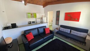 A living room with two sofas, a coffee table, and a kitchen area with a microwave and a sink. - Villa 209 sua casa em Campos do Jordão (Campos do Jordão)