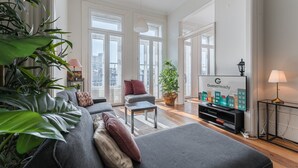 A modern living room with a grey sofa, a small table, and a TV displaying 'GuestReady'. - GuestReady - Bright Apartment near Bolhão (Porto)