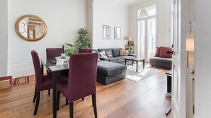 A spacious living room with a dining area, featuring a large mirror, a sofa set, and a coffee table. - GuestReady - Bright Apartment near Bolhão (Porto)