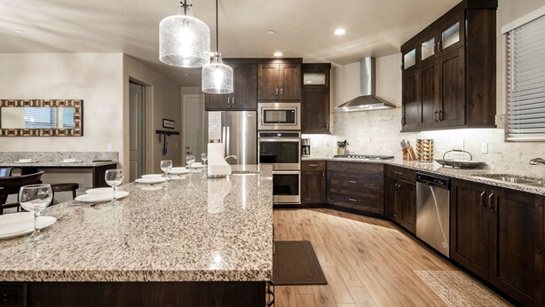 A modern kitchen with dark wood cabinets, stainless steel appliances, and a granite countertop. - Paradise Village 51, Private 20x40 Pool & Sport Court (Santa Clara)